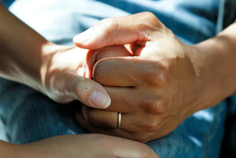 Caring clasped hands representing patient support and recovery
