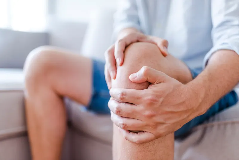 Man holding his knee in pain while seated