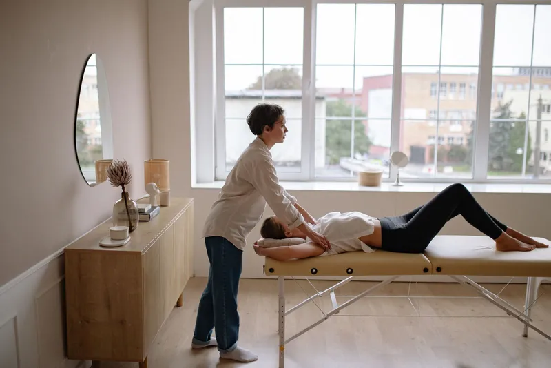 Physical therapist working with a patient on a treatment table in a bright clinic