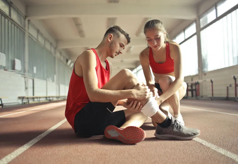 Athlete on a running track being helped after a knee injury