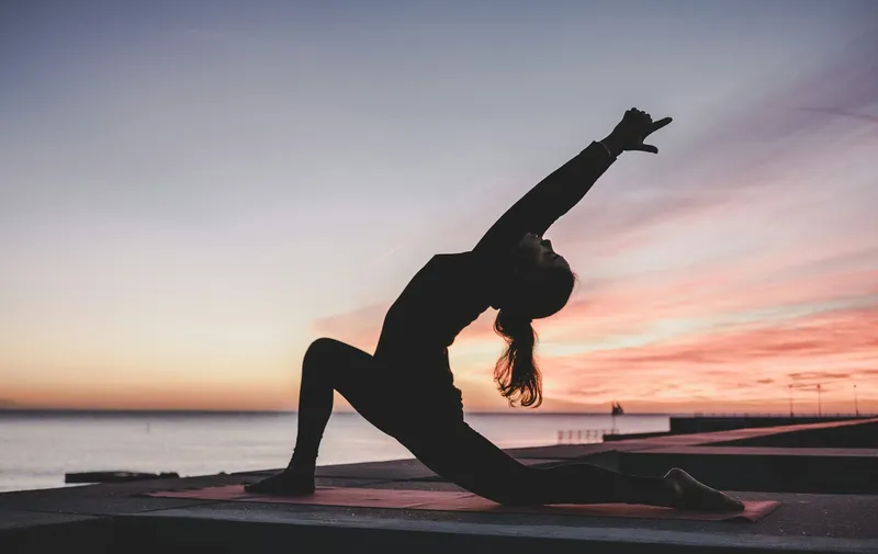 Person stretching during low-impact exercise at sunset